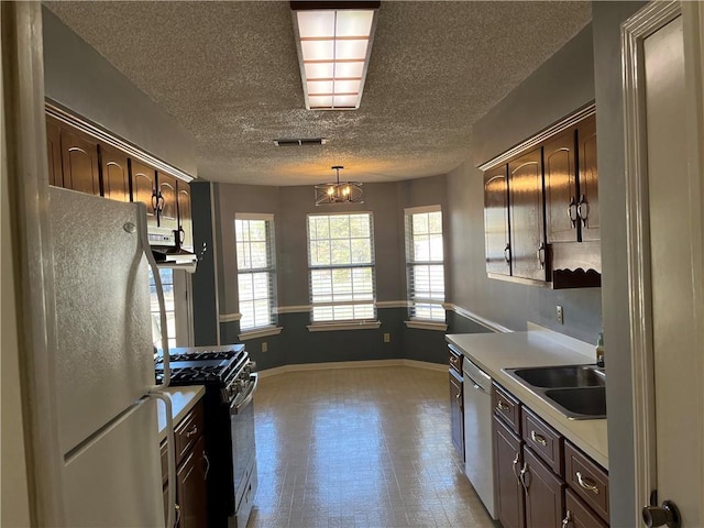 kitchen featuring white fridge, dark brown cabinets, and range with gas stovetop