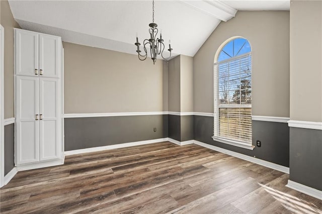 unfurnished dining area featuring lofted ceiling with beams, a notable chandelier, wood finished floors, and baseboards