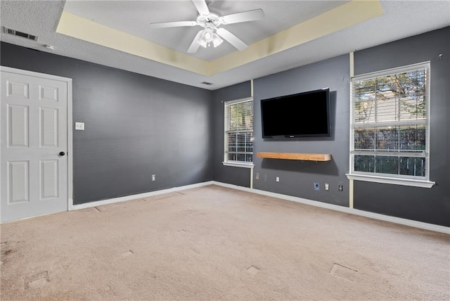 unfurnished living room featuring baseboards, visible vents, a raised ceiling, a ceiling fan, and carpet