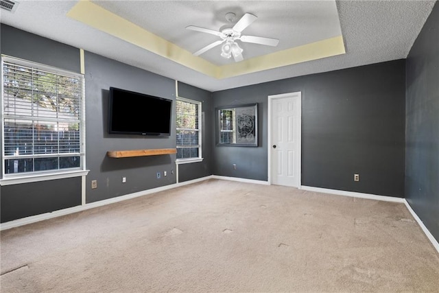 interior space with a wealth of natural light, baseboards, a raised ceiling, and carpet flooring