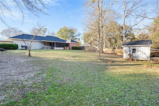 view of yard featuring fence, a storage unit, and an outdoor structure