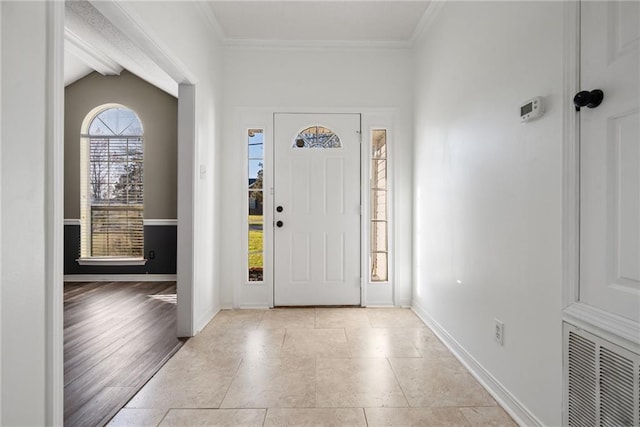 foyer entrance with crown molding, visible vents, and baseboards