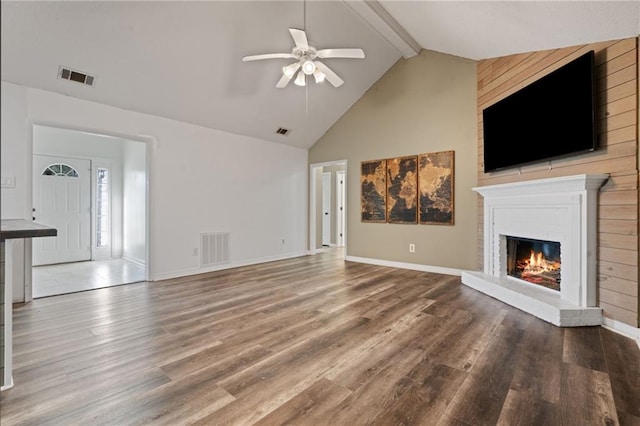 unfurnished living room featuring visible vents, wood finished floors, beam ceiling, and a glass covered fireplace