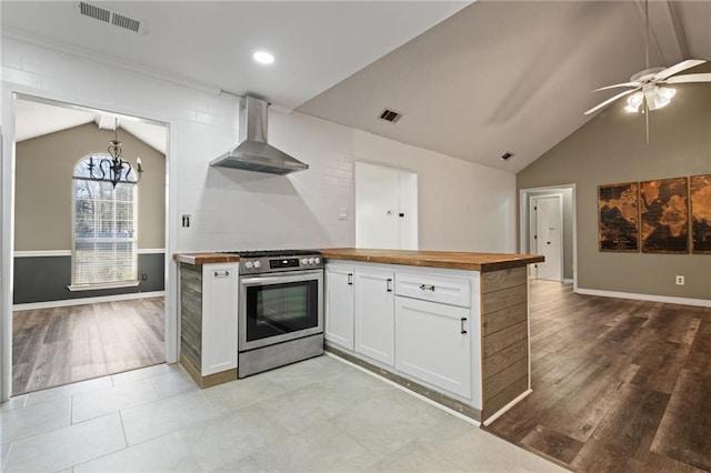 kitchen featuring butcher block countertops, gas stove, visible vents, and wall chimney range hood