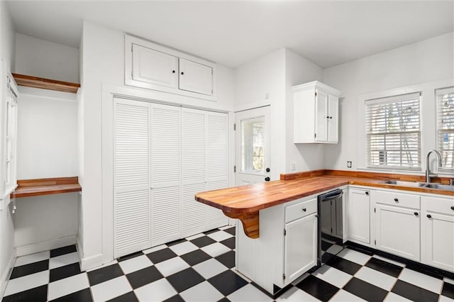 kitchen with white cabinets, black dishwasher, butcher block counters, and sink