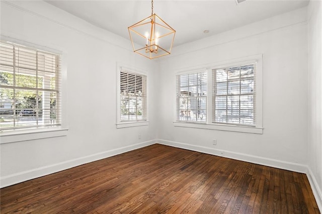 empty room with hardwood / wood-style flooring and a notable chandelier