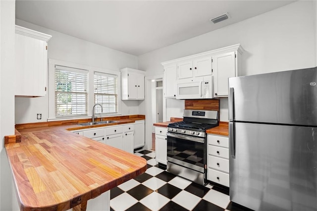 kitchen with wood counters, stainless steel appliances, white cabinetry, and sink