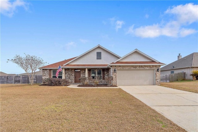 craftsman-style home with an attached garage, concrete driveway, a front lawn, and fence