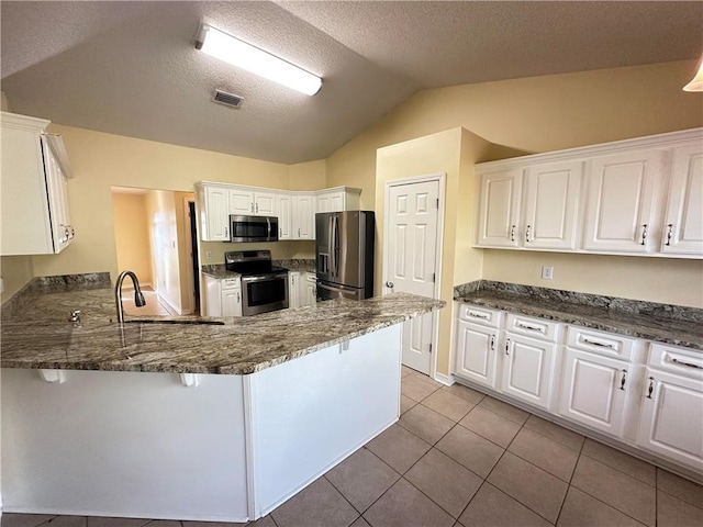 kitchen featuring stainless steel appliances, kitchen peninsula, dark stone counters, and white cabinets