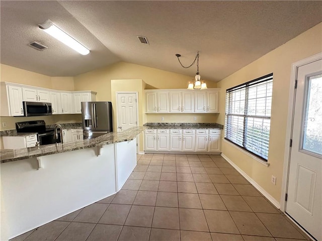 kitchen featuring white cabinetry, hanging light fixtures, a kitchen breakfast bar, dark tile patterned flooring, and stainless steel appliances