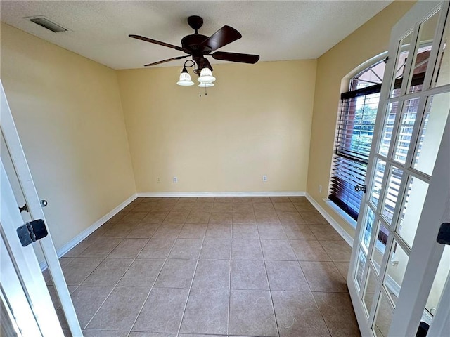 tiled empty room featuring ceiling fan and a textured ceiling