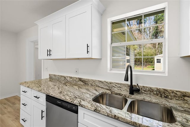 kitchen featuring light stone counters, stainless steel dishwasher, light wood-style floors, white cabinetry, and a sink