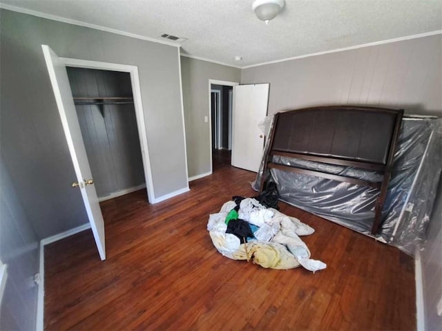 bedroom featuring crown molding, dark hardwood / wood-style flooring, a closet, and a textured ceiling