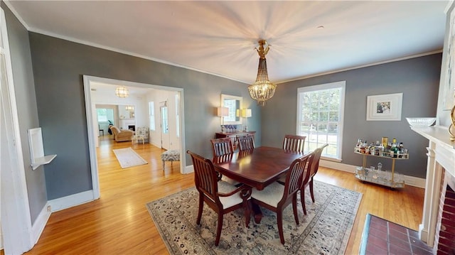 167 Glenwood St, Mobile, AL 36606 - dining room featuring a chandelier, ornamental molding, a fireplace, light wood-type flooring, and baseboards