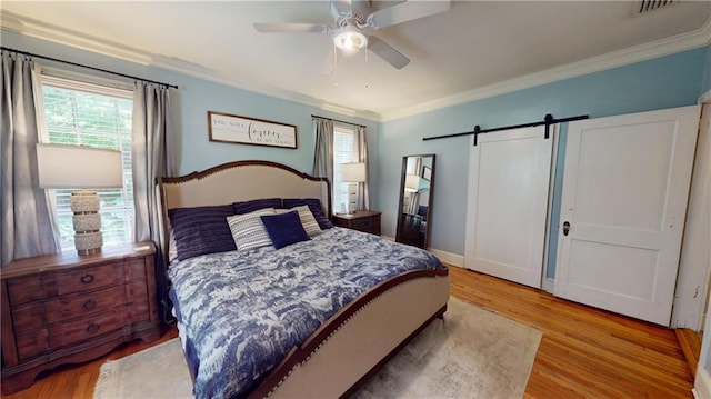 167 Glenwood St, Mobile, AL 36606 - bedroom featuring a barn door, crown molding, light wood-style floors, and ceiling fan