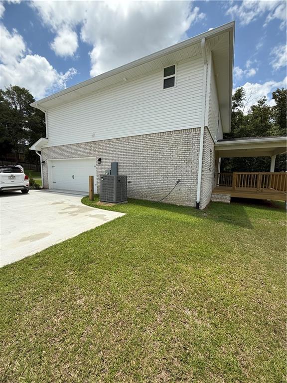 3557 Meadow Ln E, Mobile, AL 36618 - view of home's exterior with brick siding, a garage, a yard, and concrete driveway