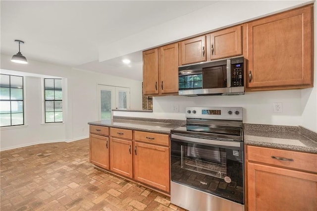 kitchen featuring dark countertops, baseboards, appliances with stainless steel finishes, and brown cabinets