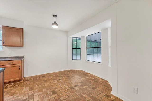unfurnished dining area featuring brick floor and baseboards