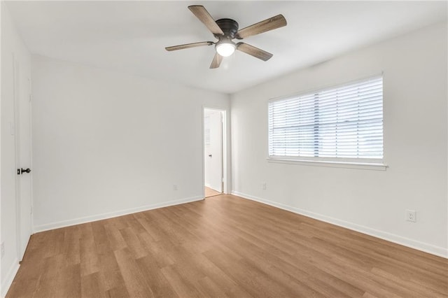 spare room featuring baseboards, a ceiling fan, and light wood finished floors