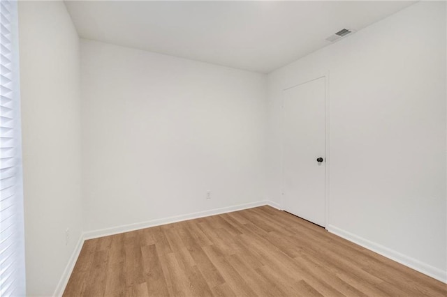 spare room with light wood finished floors, visible vents, and baseboards