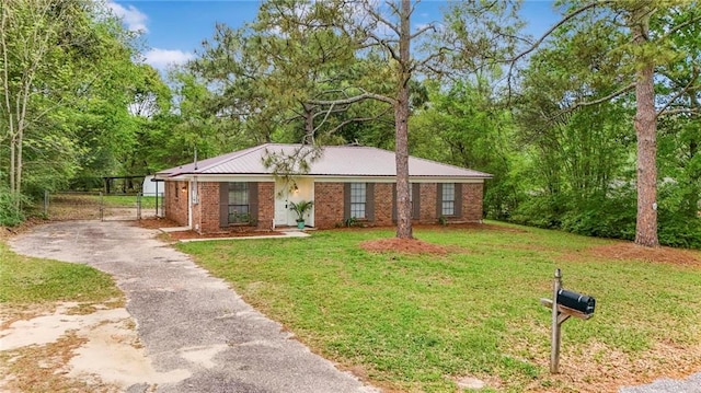 ranch-style house with metal roof, driveway, a front lawn, and brick siding