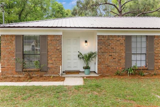 exterior space featuring metal roof, a front lawn, and brick siding
