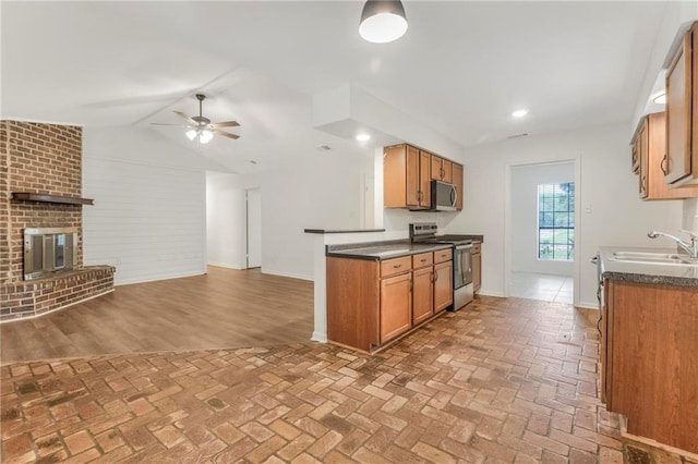 kitchen with a sink, open floor plan, ceiling fan, dark countertops, and stainless steel appliances