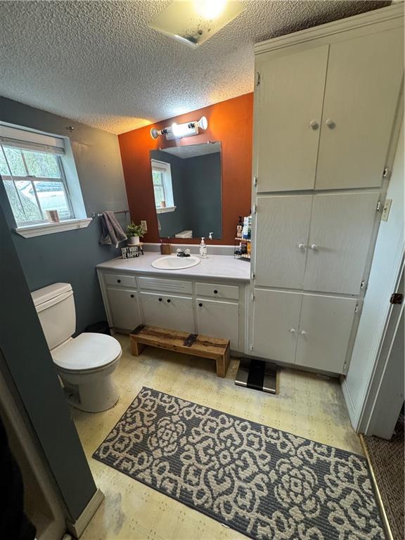 bathroom with a textured ceiling, vanity, and toilet