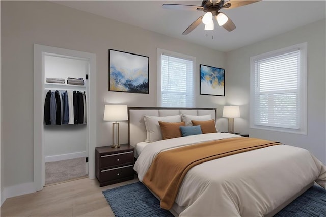 bedroom with light wood finished floors, a closet, baseboards, and multiple windows