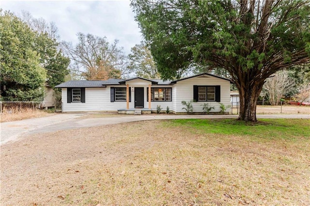 ranch-style house with driveway, fence, and a front lawn