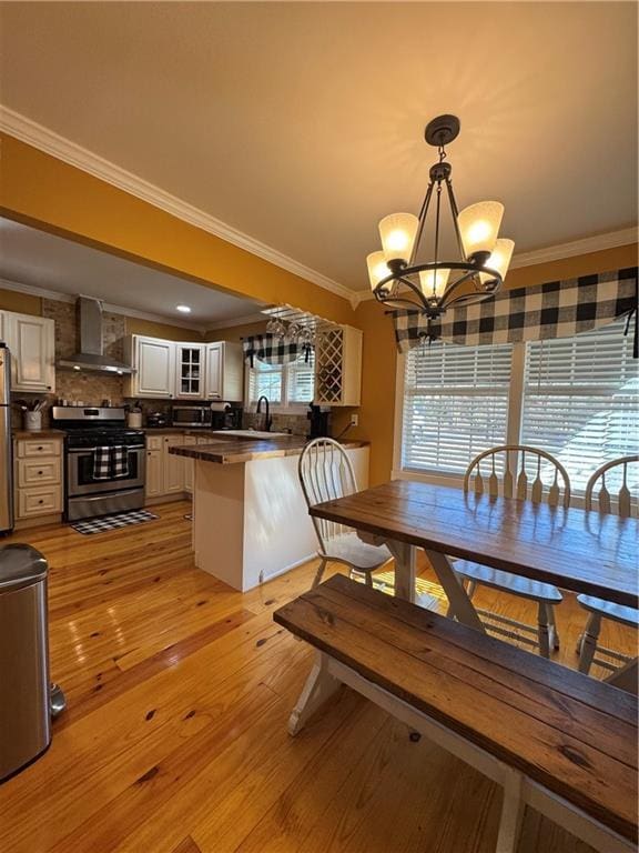 dining room with a healthy amount of sunlight, light wood-style flooring, and crown molding