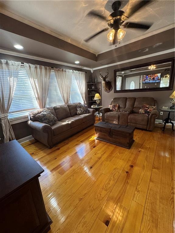 living room with ornamental molding, light wood-style flooring, and a ceiling fan