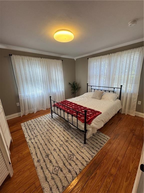 bedroom with baseboards, ornamental molding, and wood finished floors