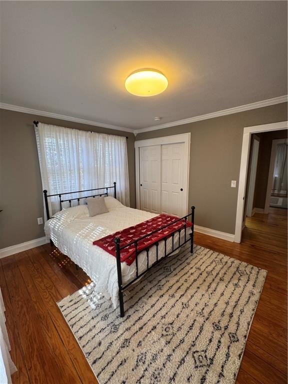 bedroom with ornamental molding and wood finished floors