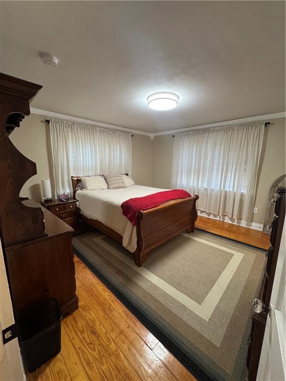 bedroom featuring ornamental molding and light wood-type flooring