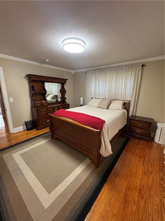 bedroom with baseboards, crown molding, and wood finished floors