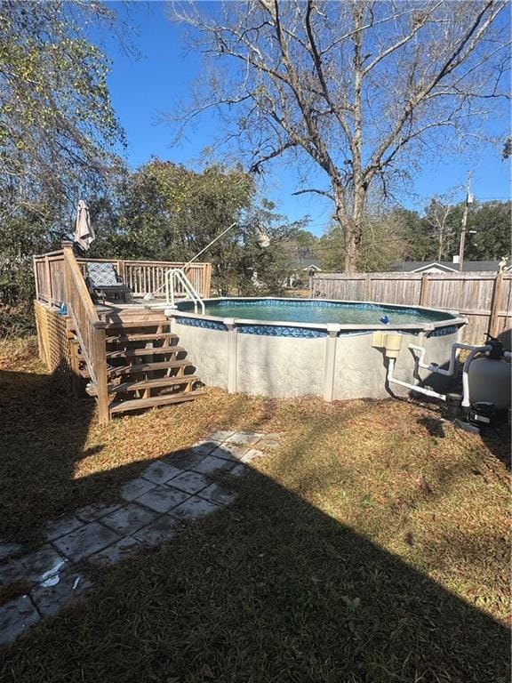 view of swimming pool featuring a deck, a yard, fence, and a fenced in pool