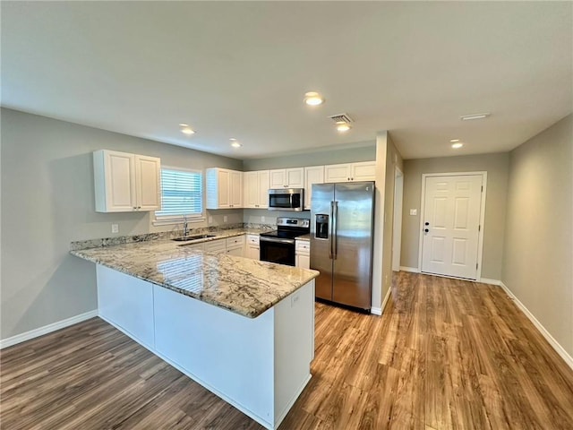 kitchen with light stone countertops, sink, stainless steel appliances, light hardwood / wood-style flooring, and white cabinets