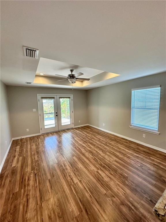 spare room featuring french doors, hardwood / wood-style flooring, ceiling fan, and a tray ceiling