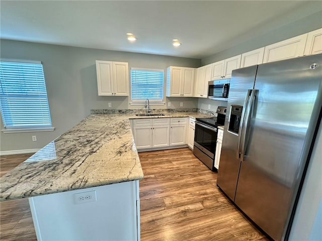 kitchen featuring white cabinets, sink, light wood-type flooring, light stone counters, and stainless steel appliances