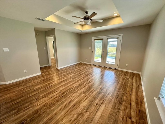 unfurnished room with french doors, a raised ceiling, ceiling fan, and hardwood / wood-style floors