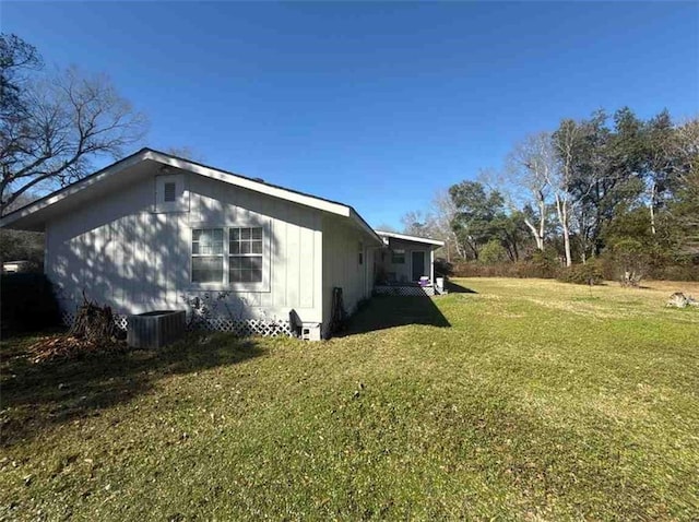 view of side of property featuring central AC and a yard