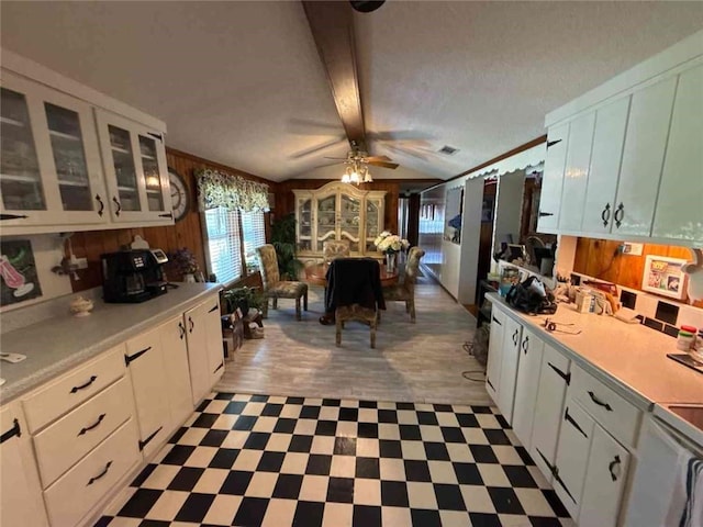 kitchen featuring white cabinets, a ceiling fan, vaulted ceiling with beams, light countertops, and light floors