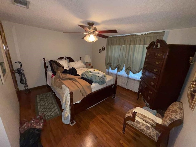 bedroom with a textured ceiling, ceiling fan, wood finished floors, and visible vents