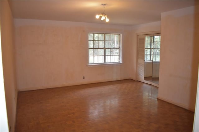 unfurnished room featuring a chandelier and parquet floors