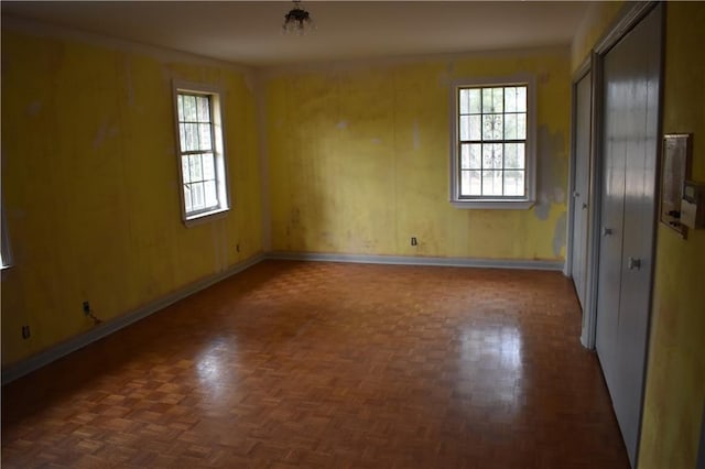 spare room featuring dark parquet floors and wood walls