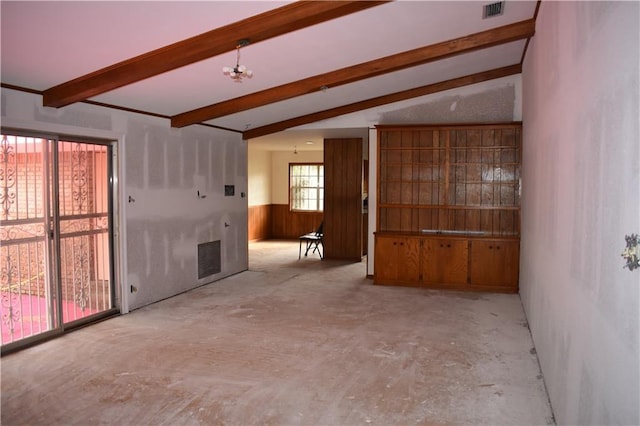 empty room featuring wood walls and lofted ceiling with beams