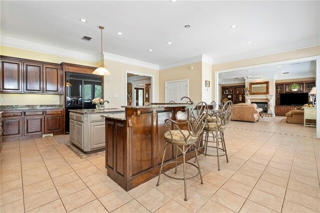 2924 Riverview Pointe Dr S, Theodore, AL 36582 - kitchen with a breakfast bar area, light tile patterned flooring, a center island with sink, crown molding, and recessed lighting