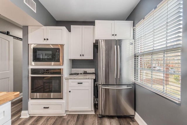 kitchen featuring white cabinetry, stainless steel appliances, and a barn door