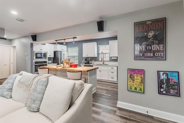 kitchen featuring wood counters, sink, white cabinetry, stainless steel appliances, and hardwood / wood-style flooring